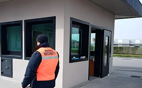 Operatore Kosmos Security con gilet arancione davanti alla guardiola d’ingresso di un sito industriale
