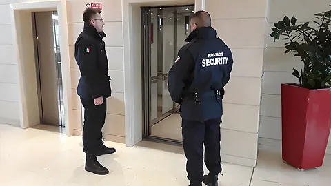 Due addetti Kosmos Security in divisa nella hall di un edificio, davanti agli ascensori
